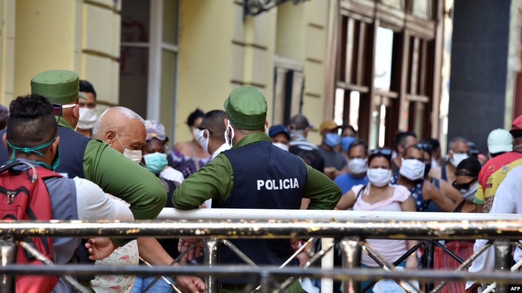Policías controlando la población en una cola para conseguir alimentos, el 12 de abril del 2020. (AFP).