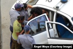 Berta Soler, vocera del movimiento opositor Damas de Blanco en La Habana, es introducida a un auto patrullero por fuerzas policiales.