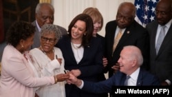 El presidente Joe Biden firma la ley junto a la vicepresidenta Kamala Harris y colegas del Concilio Negro del Congreso. (Jim Watson / AFP).