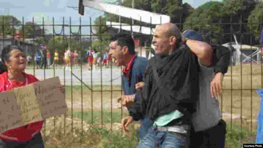 Arresto en Sagua La Grande del opositor Luis E Santos, a su lado Onelia Alonso activista de la Coalición Central Opositora porta una cartel pidiendo la libertad del preso político Enrique Esteban Prieto. De los activistas que participaron nueve fueron detenidos y liberadso horas después según destacó Maria del Carmen Hernández que se retiró de la protesta para poder salvar las imágenes del arresto.