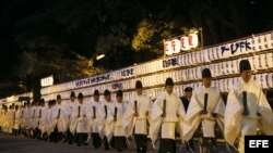 Varios sacerdotes sintoístas abandonan la sala de adoración y dejan atrás la puerta sur tras finalizar un ritual sintoísta de preparación para la llegada del Año Nuevo 2013 en el templo Meiji de Tokio (Japón).