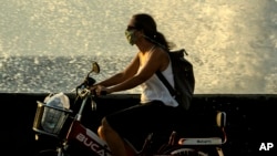 Una mujer se traslada en bicicleta por el Malecón habanero en medio de la pandemia de coronavirus. (AP/Ramon Espinosa)