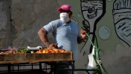 Un vendedor de vegetales en una calle de La Habana usa una máscara para protegerse del coronavirus. (YAMIL LAGE / AFP)