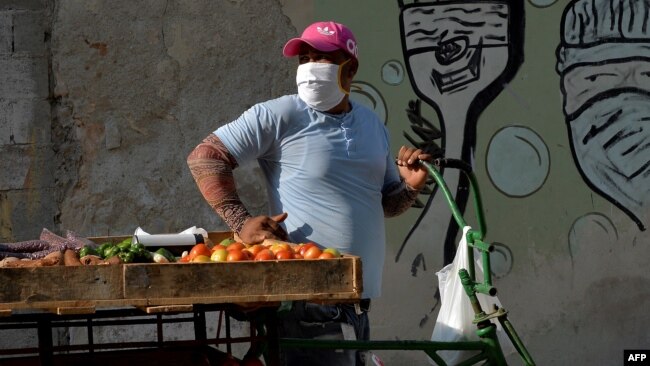 Un vendedor de vegetales en una calle de La Habana usa una máscara para protegerse del coronavirus. (YAMIL LAGE / AFP)