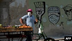 Un vendedor de vegetales en una calle de La Habana usa una máscara para protegerse del coronavirus. (YAMIL LAGE / AFP)