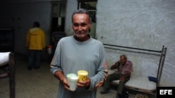 ARCHIVO. Un hombre camina con unos vasos de leche en un albergue organizado en una escuela.