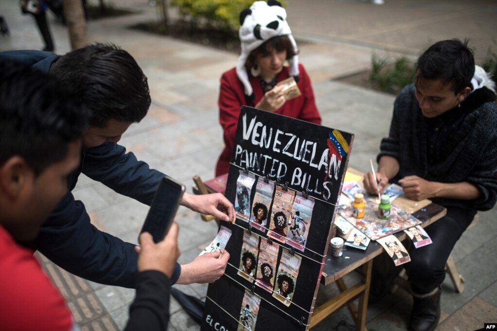 Una pareja de migrantes venezolanos pinta billetes en las calles de Bogotá para protestar contra la situación económica de su país. (Archivo)