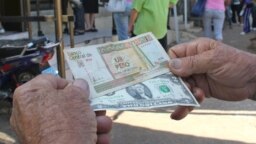 Un hombre muestra un peso convertible cubano y un dólar estadounidense. (Archivo)