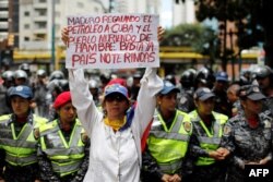 Una mujer en Caracas sostiene un cartel donde critica a Maduro por enviar petróleo a Cuba.