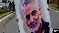 Un hombre carga el retrato del general iraní Qassem Soleimani, abatido por EEUU. 
