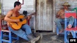  Un miembro de la comunidad de los "Acuáticos" ubicada en el Valle de Viñales, en la occidental provincia de Pinar del Río, toca la guitarra en el portal de su casa. 