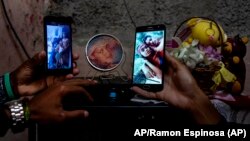 Familiares muestran fotos de los hermanos Román, en prisión por manifestarse el 11 de julio en La Güinera. (AP Foto/Ramón Espinosa)