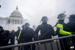 Partidarios de Trump intentan atravesar una barrera policial en el Capitolio de Washington. (AP/Julio Cortez)
