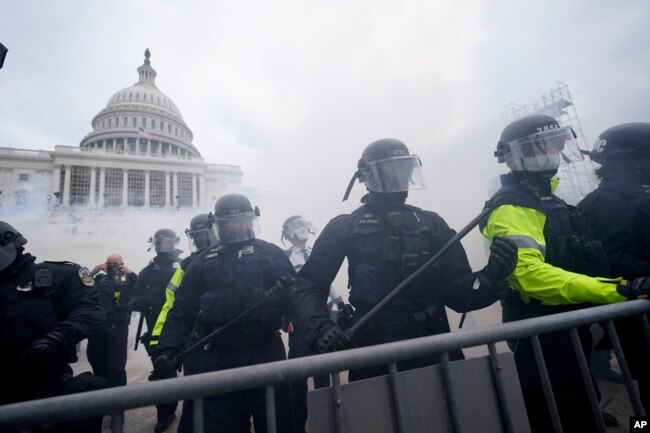 Partidarios de Trump intentan atravesar una barrera policial en el Capitolio, de Washington. (AP/Julio Cortez)
