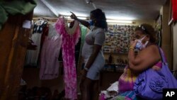 Una mujer espera que le muestren un vestido en una tienda privada de ropa y artesanías en La Habana. (AP Foto/Ramón Espinosa, Archivo)