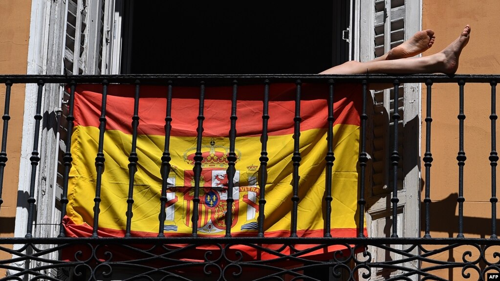 Una mujer toma el sol en su balcón en Madrid detrás de una bandera española. (Gabriel BOUYS / AFP)