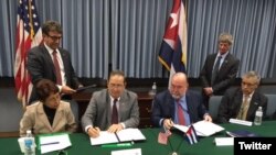 Funcionarios de EEUU y Cuba firman el acuerdo en Washington.