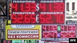 Varias personas caminan junto a un cartel que indica el cambio de divisa en Moscú, Rusia.