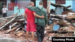 Dos pinareños contemplan las ruinas de una casa derrumbada por el huracán Michael.
