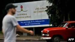 Un cubano camina cerca de un poster donde se anuncia la Reforma Constitucional.