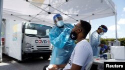 Un trabajador de la salud realiza una prueba PCR a un hombre en un sitio de prueba móvil de COVID-19 en el condado de Manatee, en Palmetto, Florida.