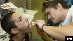 La dentista Anne Solcis (dcha.) chequea la boca de Miguel Cruz de 13 años, durante examenes físicos en Arizona