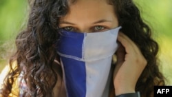 Una estudiante nicaragüense usa la bandera como máscara durante una protesta en la UCA.