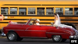 Una pareja de recién casados viaja en un viejo auto descapotable.