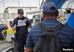 Un oficial de Aduanas y Protección de Fronteras inspecciona los documentos de un migrante hondureño en busca de asilo en EEUU.