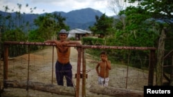 El campesino Javier Tamayo, 55, posa junto a su nieto en su casa en la Sierra Maestra. REUTERS/Alexandre Meneghini 