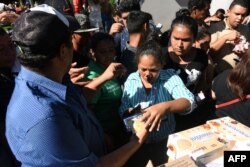 Hondureños que forman parte de la caravana de migrantes reciben comida en una plaza de Tapachula, Chiapas, México.