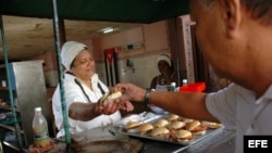 Una mujer vende pan con cerdo en un puesto callejero en La Habana (Cuba).