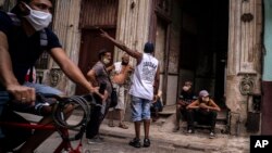Residentes se reúnen en la acera, a la entrada de un edificio, en medio del calor intenso de estos días en La Habana. (AP/Ramon Espinosa)