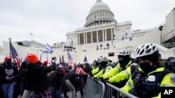 Partidarios de Trump intentan romper una barrera policial en el Capitolio, en Washington. (AP Photo/Julio Cortez)