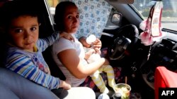 Una mujer espera junto a sus hijos pequeños para comprar gasolina en una estación de Guadalajara.