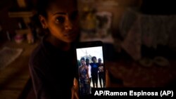 María Carla Milán Ramos muestra una foto en su teléfono de su esposo y hermanos, todos en prisión por participar el 11 de julio del 2021. (AP/Ramón Espinosa).