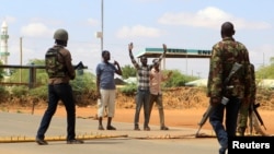 Oficiales de seguridad interrogan a civiles en la carretera donde los médicos fueron secuestrados. en Mandera Kenia.