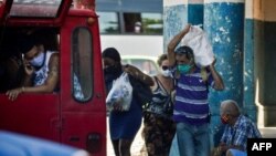 Cubanos cargan sus compras. YAMIL LAGE / AFP