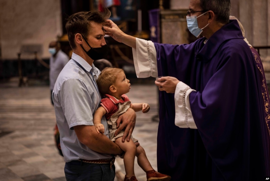 Ein Mann mit Maske, trägt seinen Sohn zur Auferlegung der Asche während der Messe am Aschermittwoch in Havanna. | Bildquelle: Radio Televisión Martí | Bilder sind in der Regel urheberrechtlich geschützt