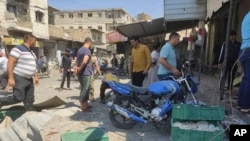 Residentes revisando un mercado atacado con cohetes en la ciudad de al-Bab, en el norte de Siria, el 19 de agosto del 2022. Quince personas murieron y decenas resultaron heridas en el ataque. (Defensa Civil Siria vía la agencia AP)