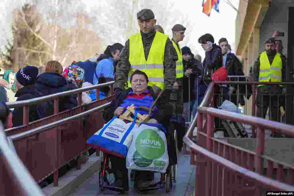Un militar ayuda a una anciana en silla de ruedas en una estación de trenes en Przemysl, Polonia. Foto: AP/Sergei Grits.
