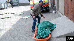 Voluntario traslada cadáver de una anciana víctima de bombardeo ruso en la región de Mykolaiev, Ucrania.
