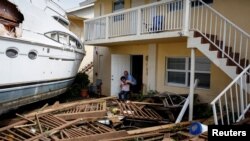 Un hombre ayuda a una mujer a salir de una casa afectada por el paso del huracán Ian, en Fort Myers, Florida.